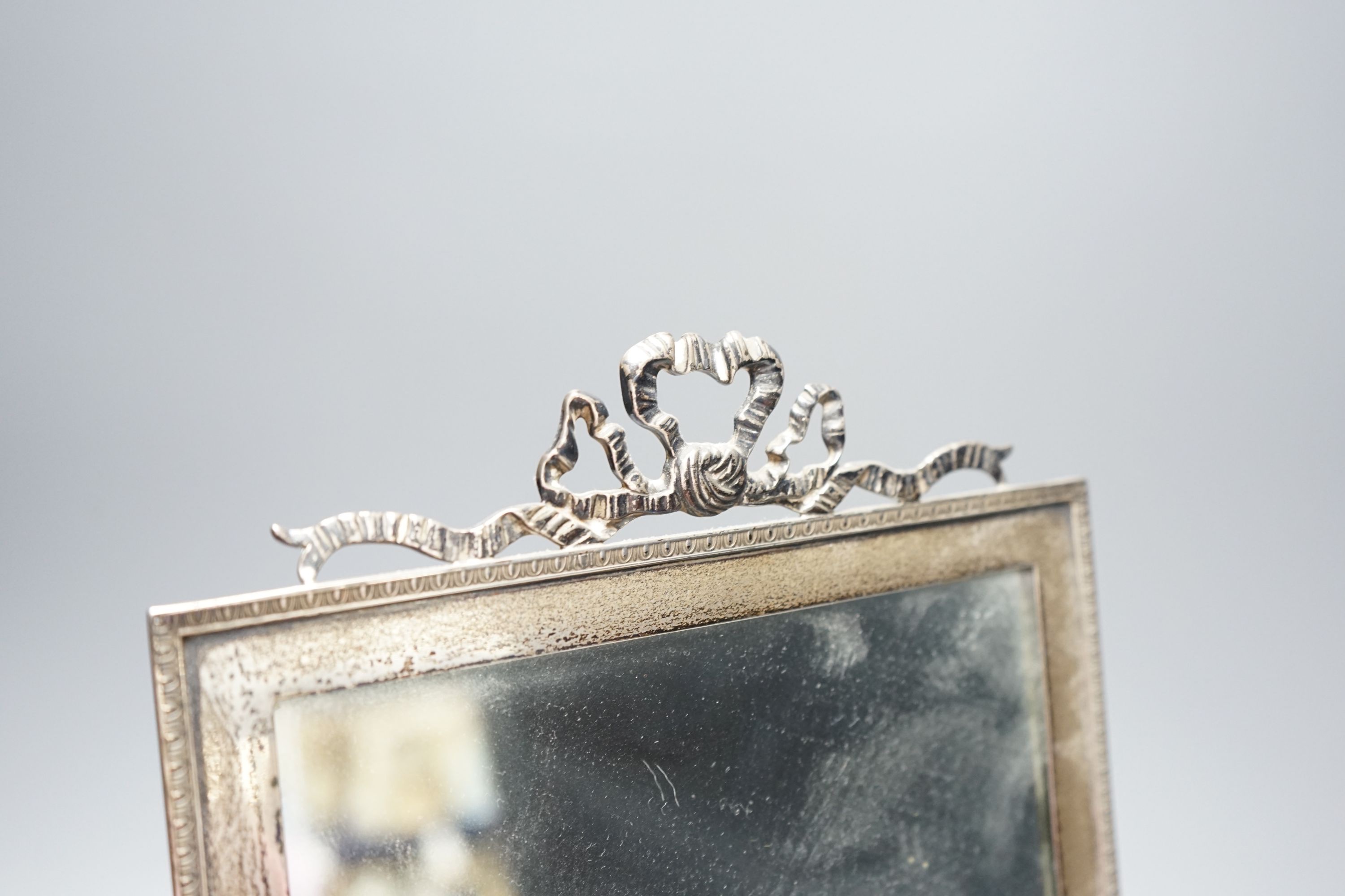 A George V silver mounted rectangular easel mirror, with ribbon bow crest, Stokes & Ireland Ltd, London, 1910, overall 35cm.